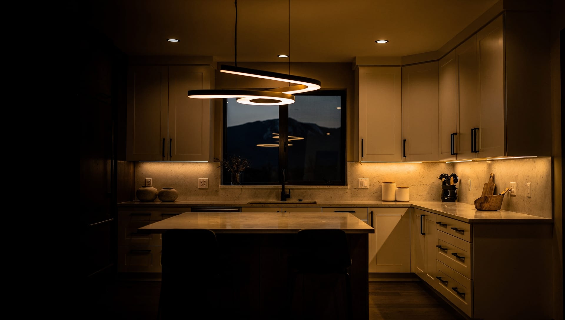 A modern Colorado kitchen at dusk lit by warm recessed and under-cabinet lighting